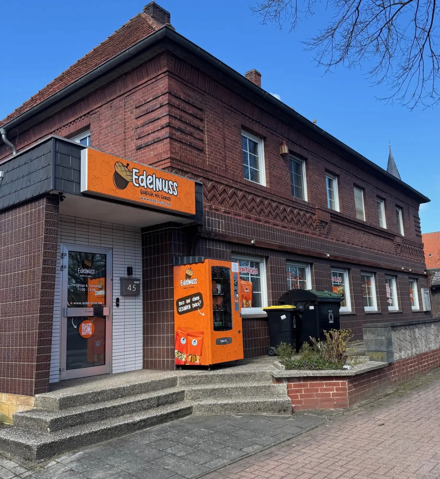 Orange Verkaufsautomat mit einem Cartoon-Nuss-Gesicht-Design und Branding mit „edelnuß“.